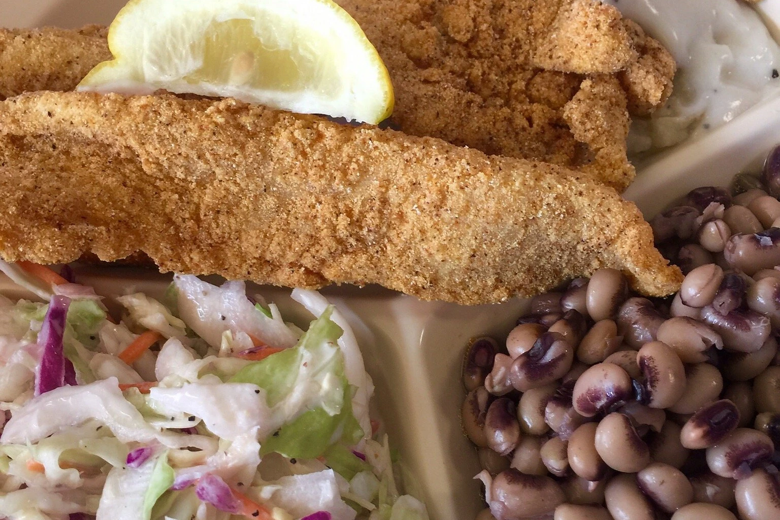 Fried catfish fillet plate with cole slaw and black-eyed peas