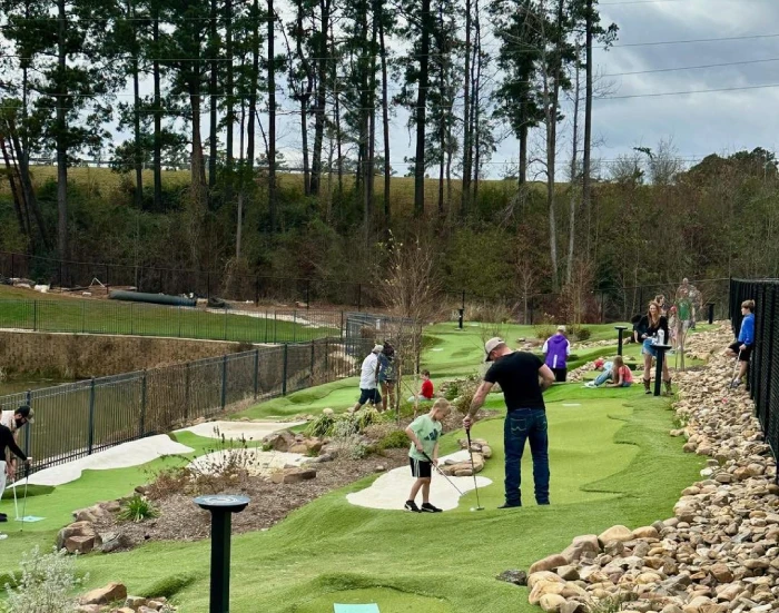 Families playing the outdoor putting course at Cargo TX