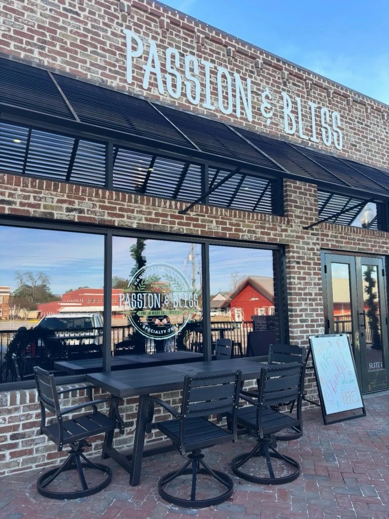 Front patio and entrance of Passion & Bliss with outdoor seating and brick storefront in Leesburg, GA