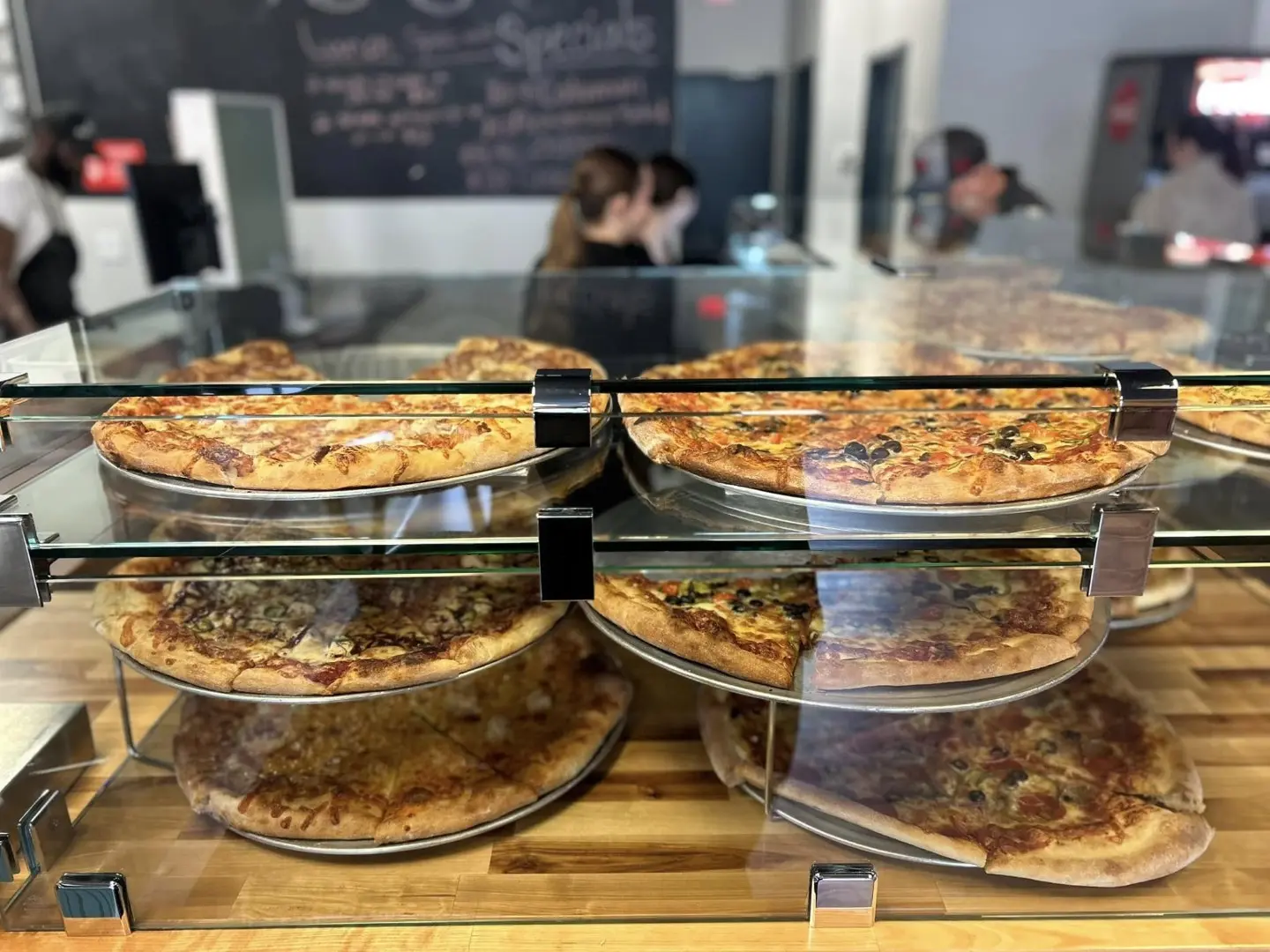variety of fresh pizzas in glass case ready for sale