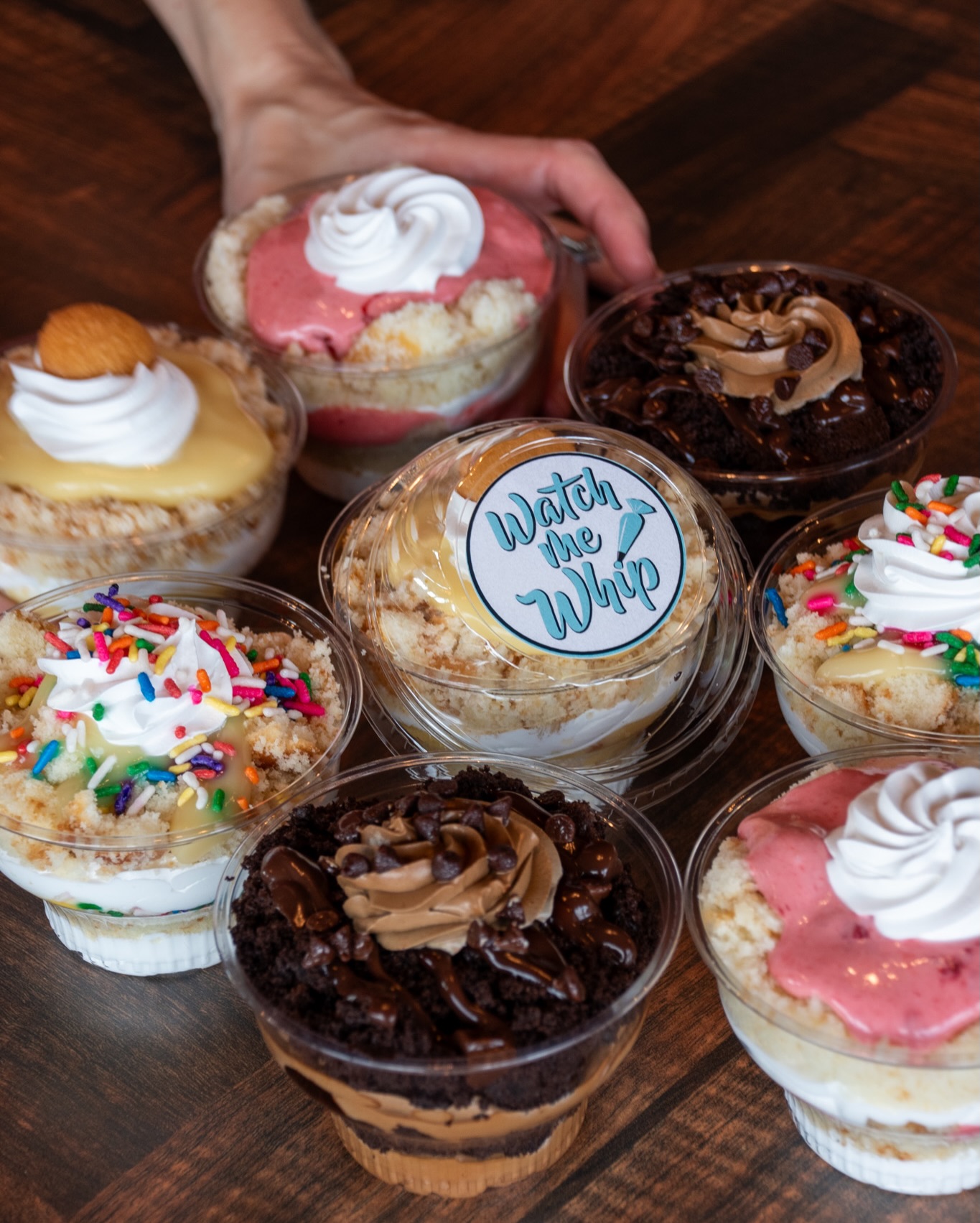 variety of cakes in a cup with hand holding one
