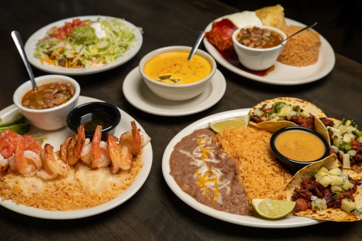 Tex-Mex spread with a taco salad, enchiladas, grilled shrimp over rice, al pastor tacos with queso, and bowls of soup at Primo's Tex Mex Grille
