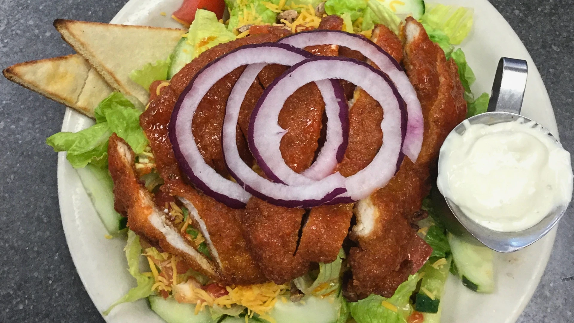 Crispy chicken salad topped with red onions, cheddar cheese, and ranch dressing