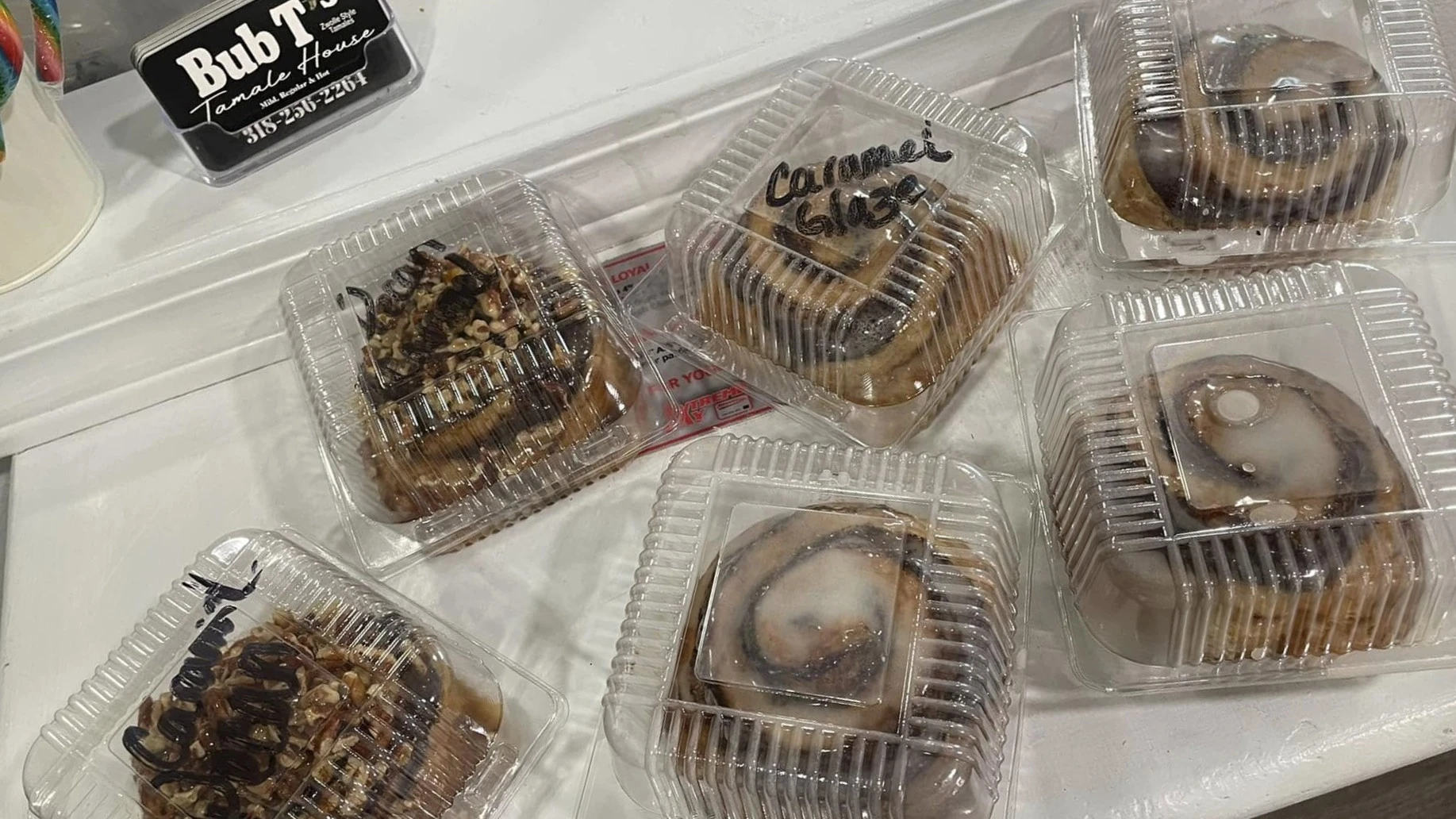 Packaged cinnamon rolls and pastries in clear plastic containers displayed on a counter