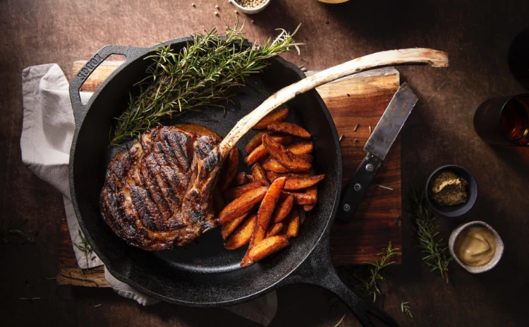 Lollipop steak inside a pan with sweet potato fries.