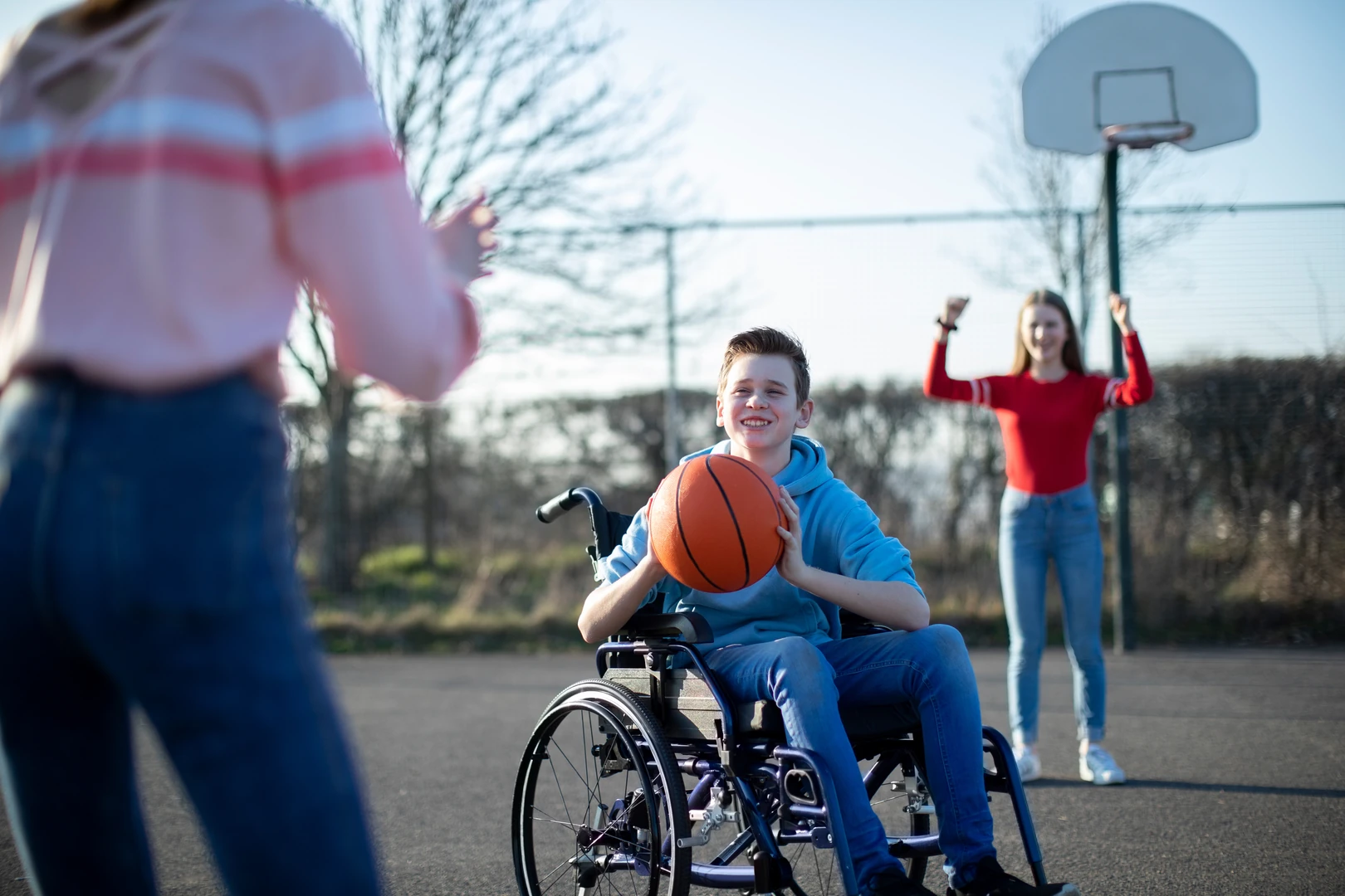 Teen in a wheelchair playing basketball with friends