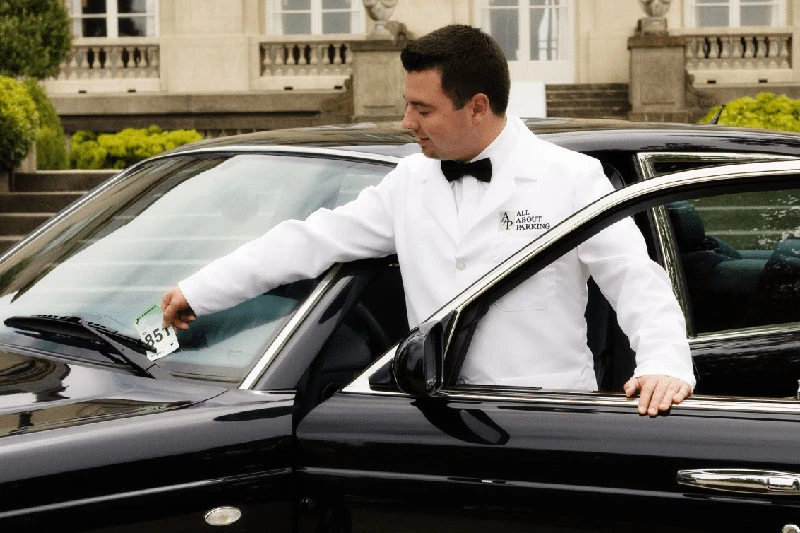 A valet attendant opening a car door at an event entrance