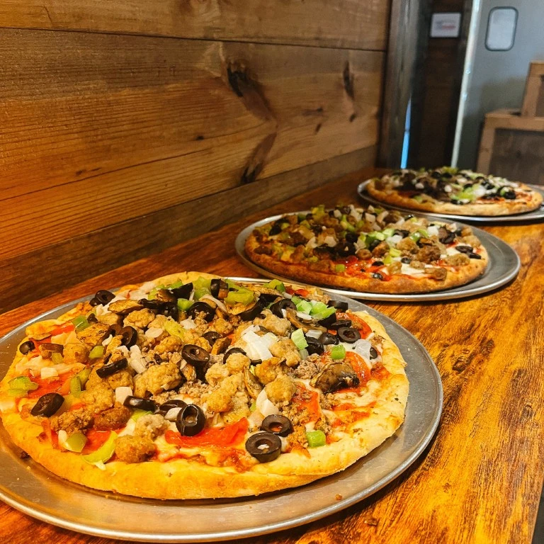 three pizzas on a wooden table