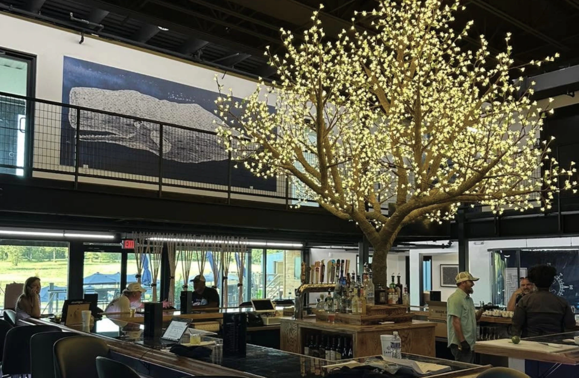 Interior bar at Cargo TX featuring a large illuminated tree centerpiece with guests enjoying drinks