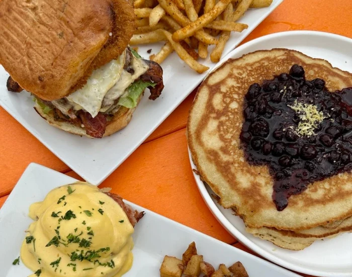 Brunch spread of a bacon burger with fries, blueberry pancakes and eggs Benedict at Cargo TX