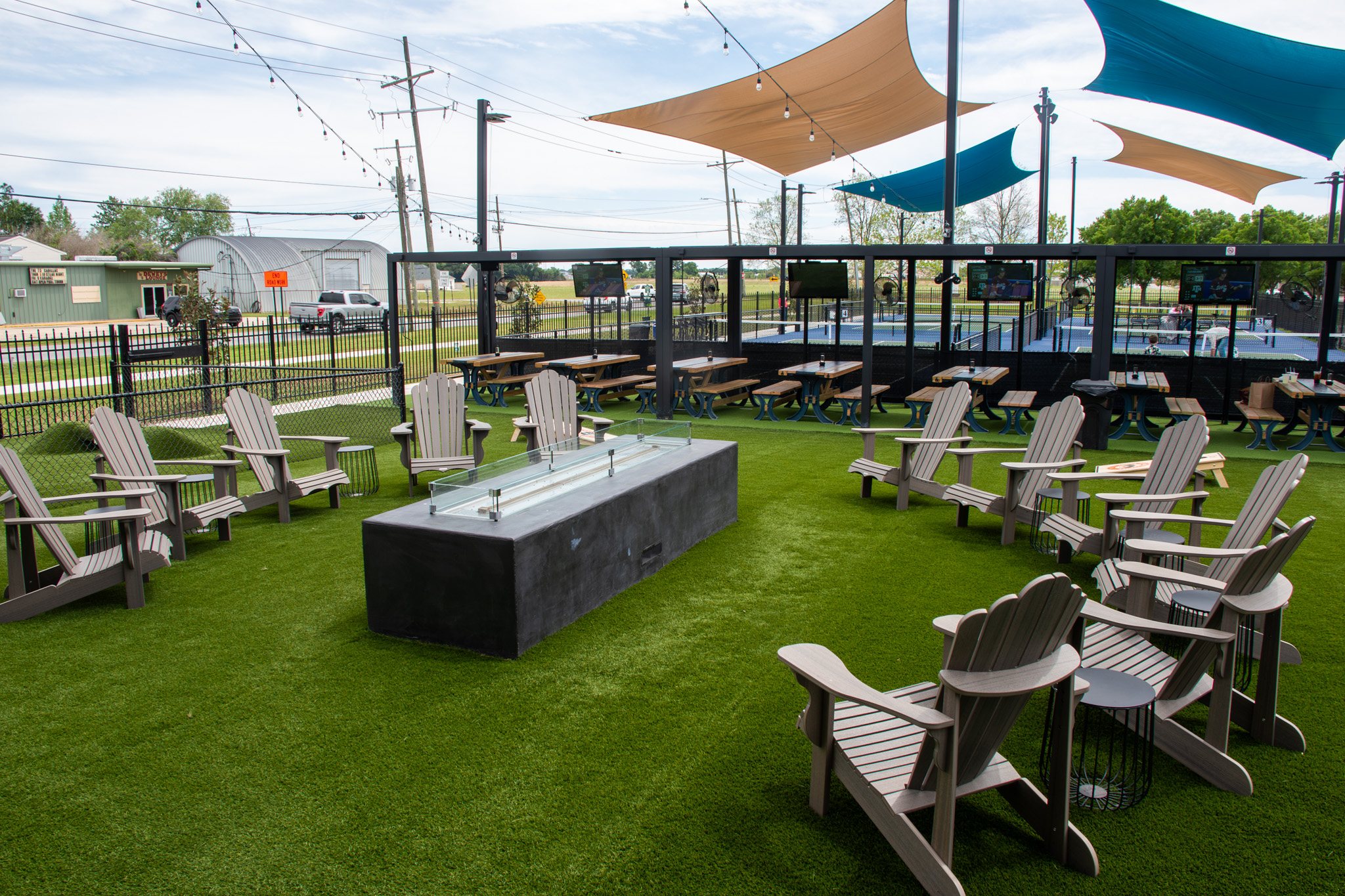 Turf area with a long fire table surrounded by Adirondack chairs