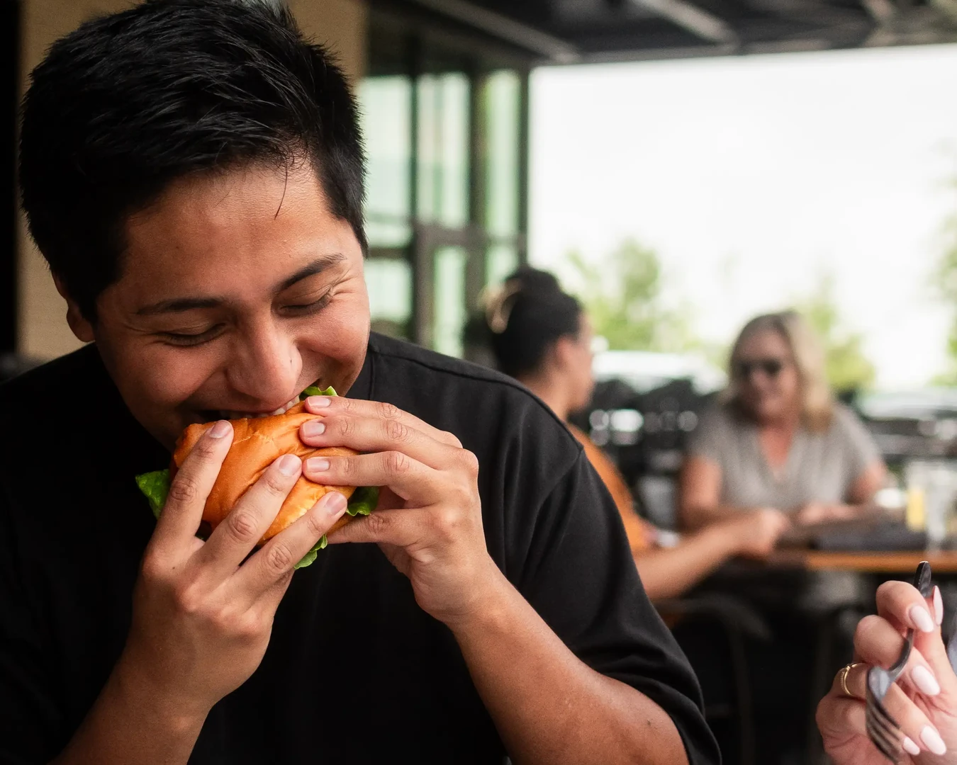 A guest enjoying a burger on the patio at The Common Table in Frisco, TX