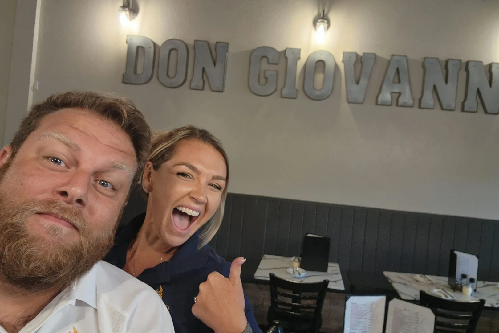 Owners of Don Giovanni standing infront of logo sign.