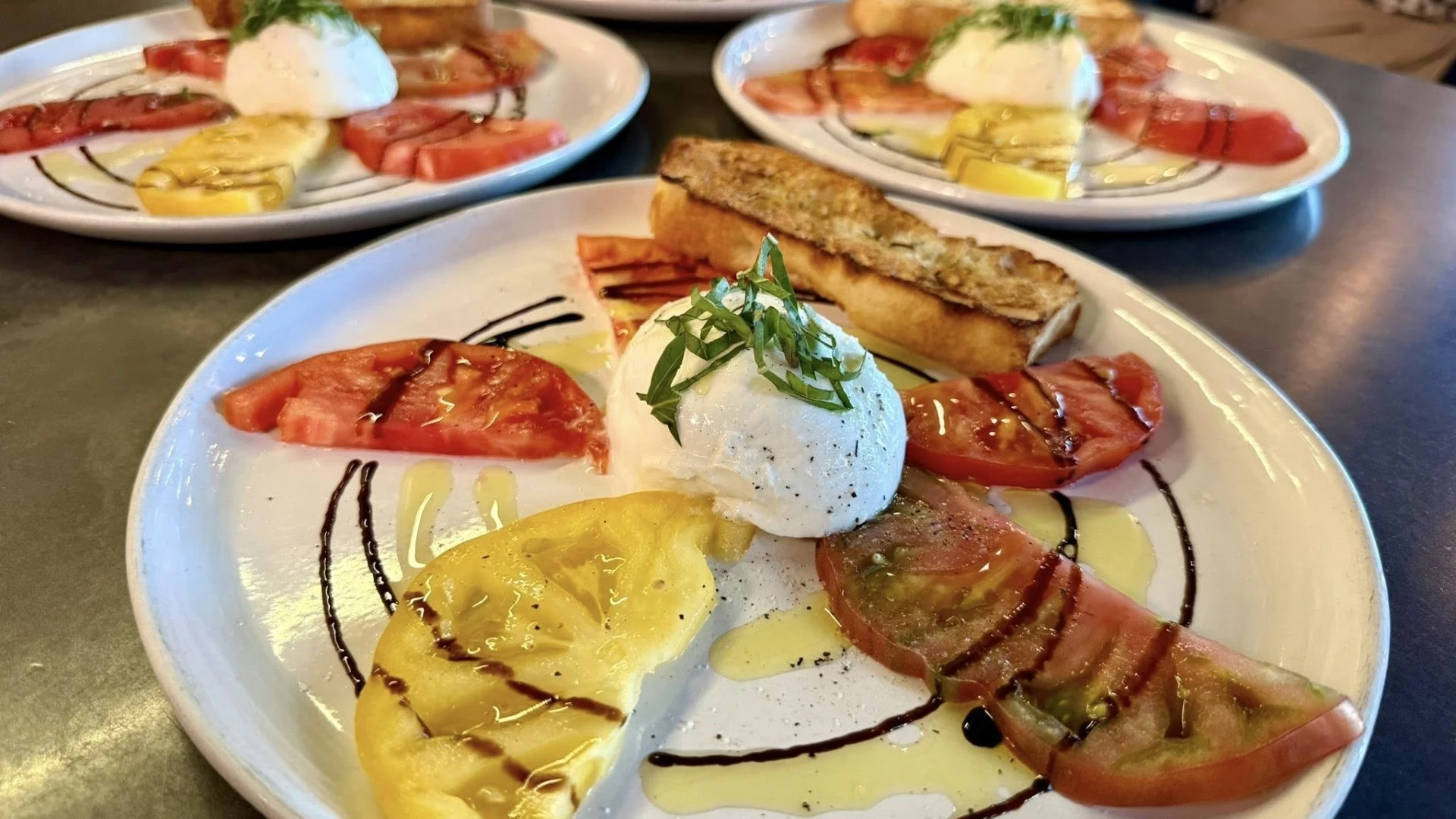Caprese-style plate with fresh mozzarella, sliced tomatoes, basil, olive oil, and balsamic glaze