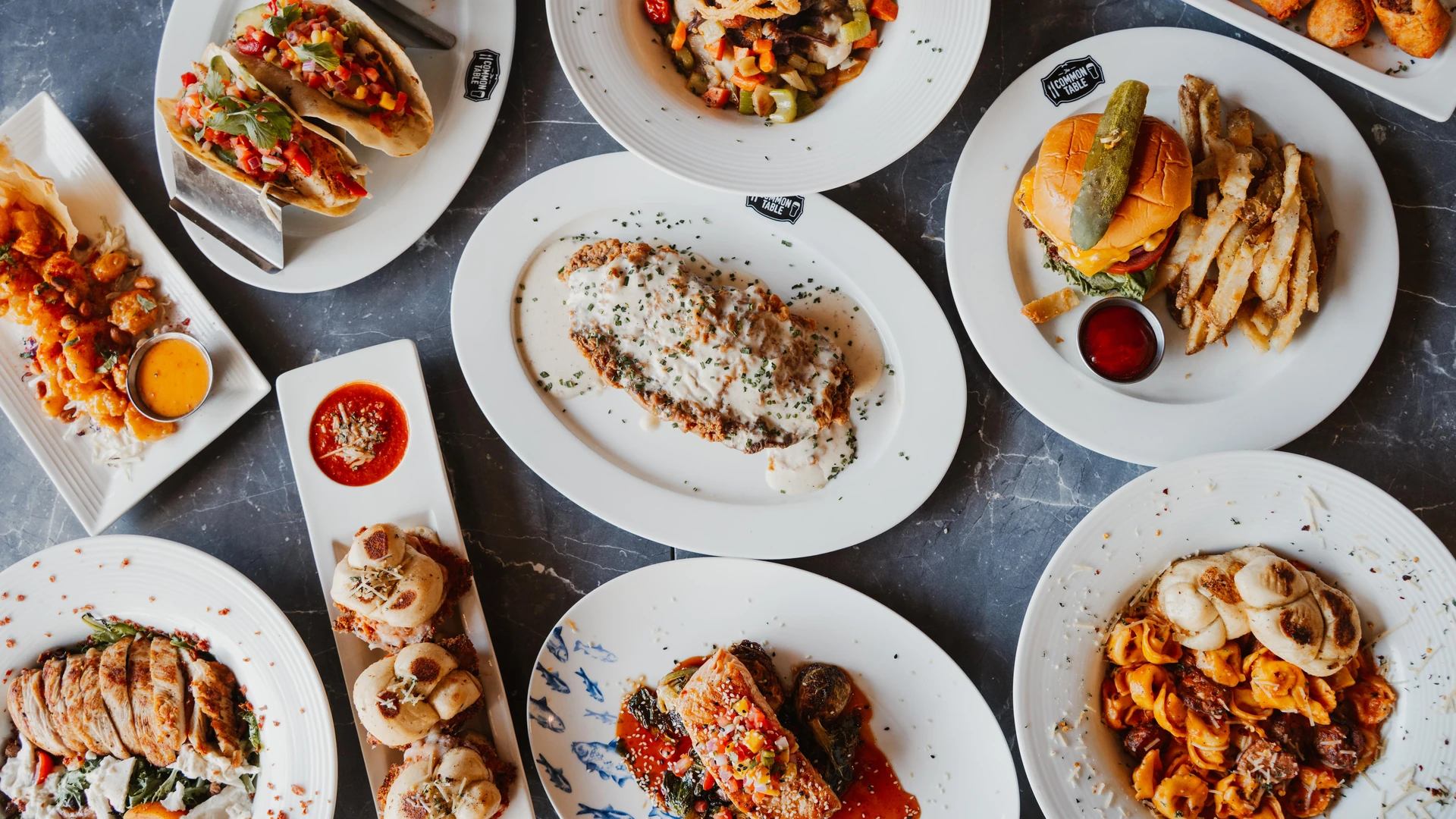 An overhead spread of tacos, burgers, pasta and shareable plates at The Common Table