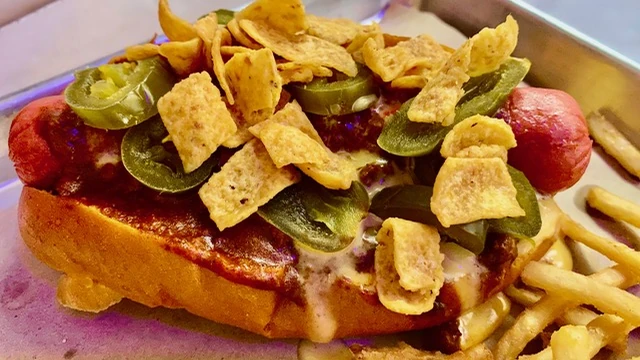 Hot dog topped with chili, jalapenos and Fritos