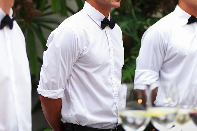 Tuxedo waiters in white shirts and bow ties before service