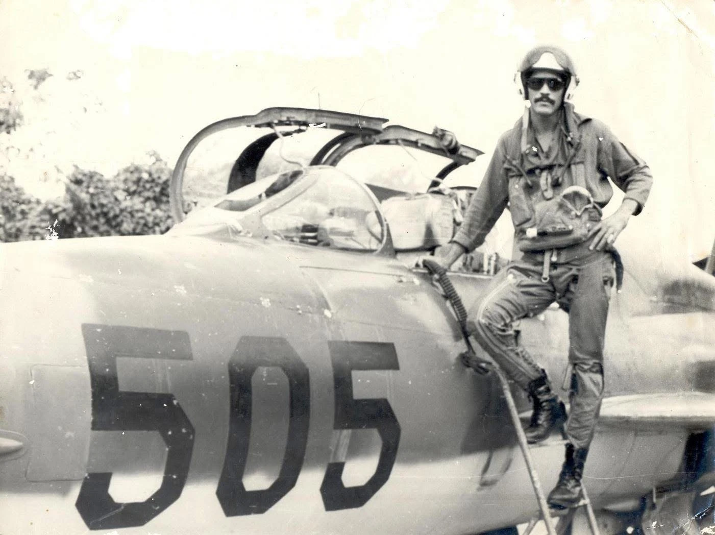 A fighter pilot standing outside his plane with a 505 on the side of it