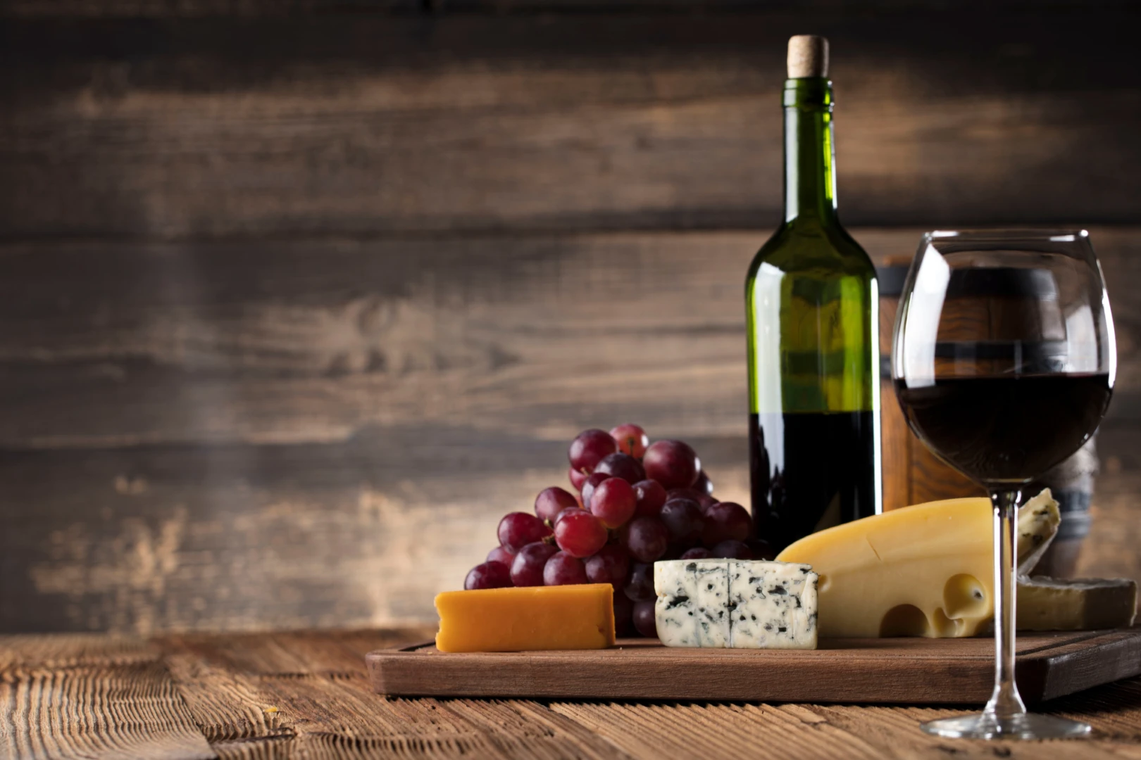 wine, cheese, and grapes on a cutting board