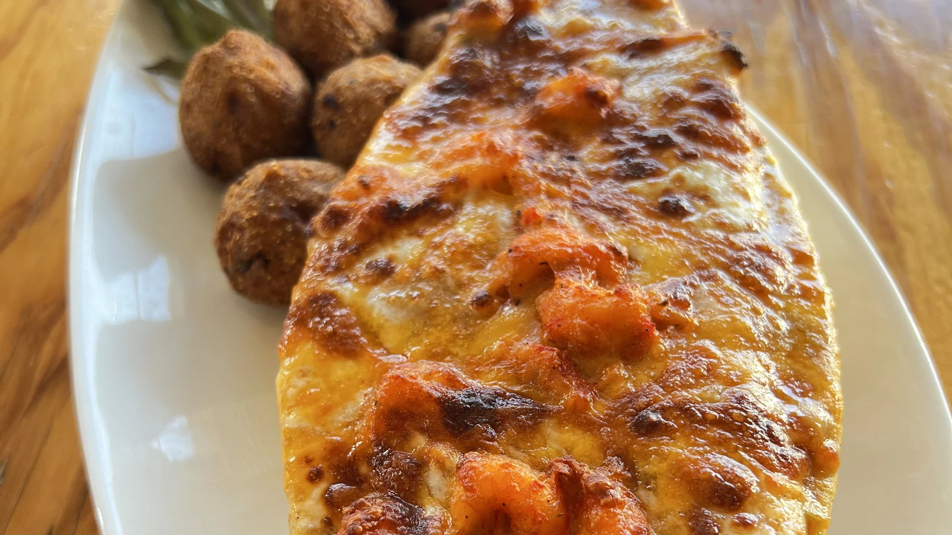 Baked seafood casserole with shrimp and melted cheese served with hush puppies.