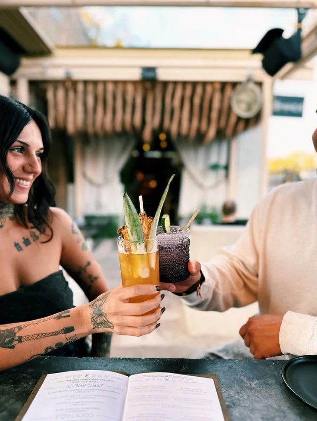 Two guests toasting cocktails on the patio at Nomade Cocina