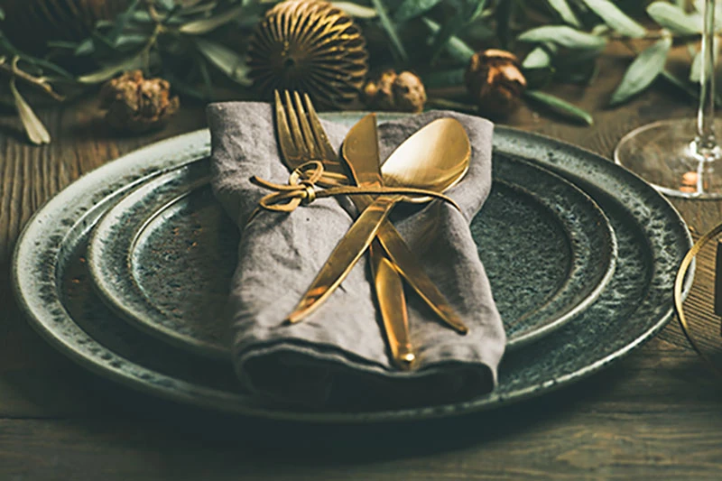 A holiday place setting with gold flatware