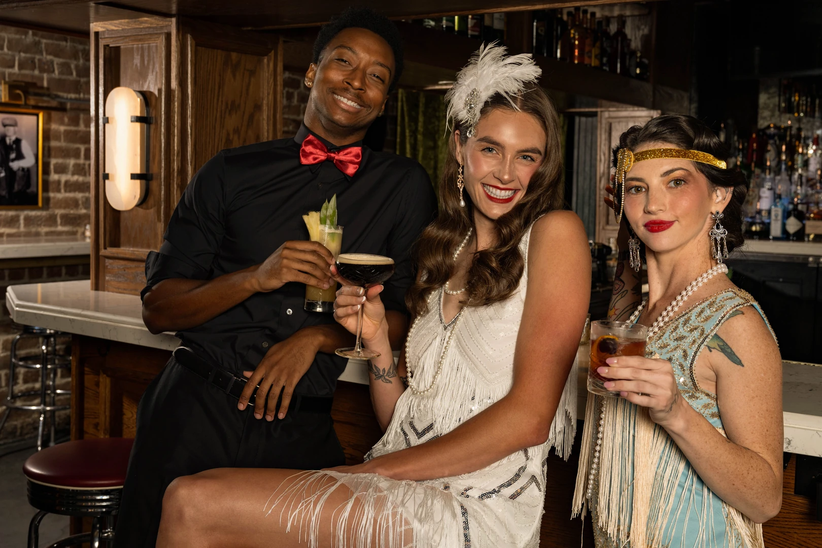 Guests in 1920s attire raising cocktails at The Bootlegger Speakeasy