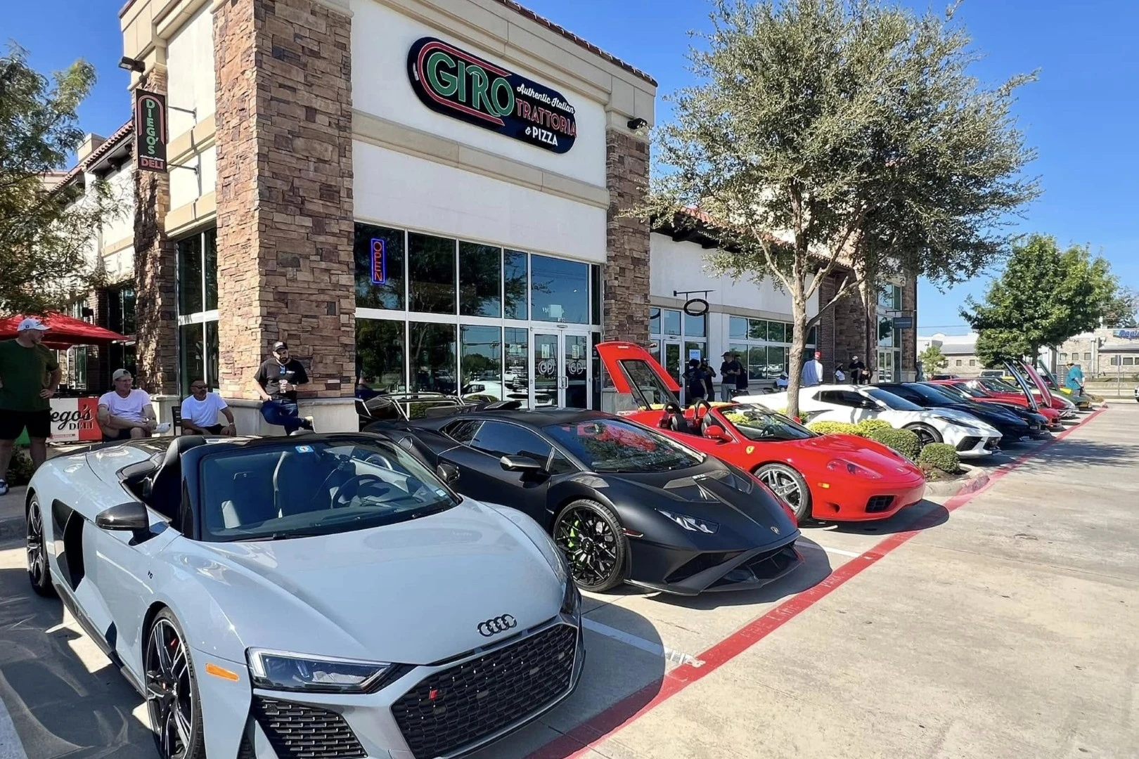 Exterior of Giro Trattoria & Pizza with a lineup of luxury sports cars parked outside
