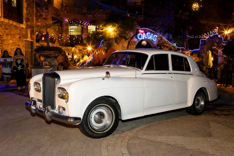 Vintage white Rolls-Royce at The Oasis entrance in the evening