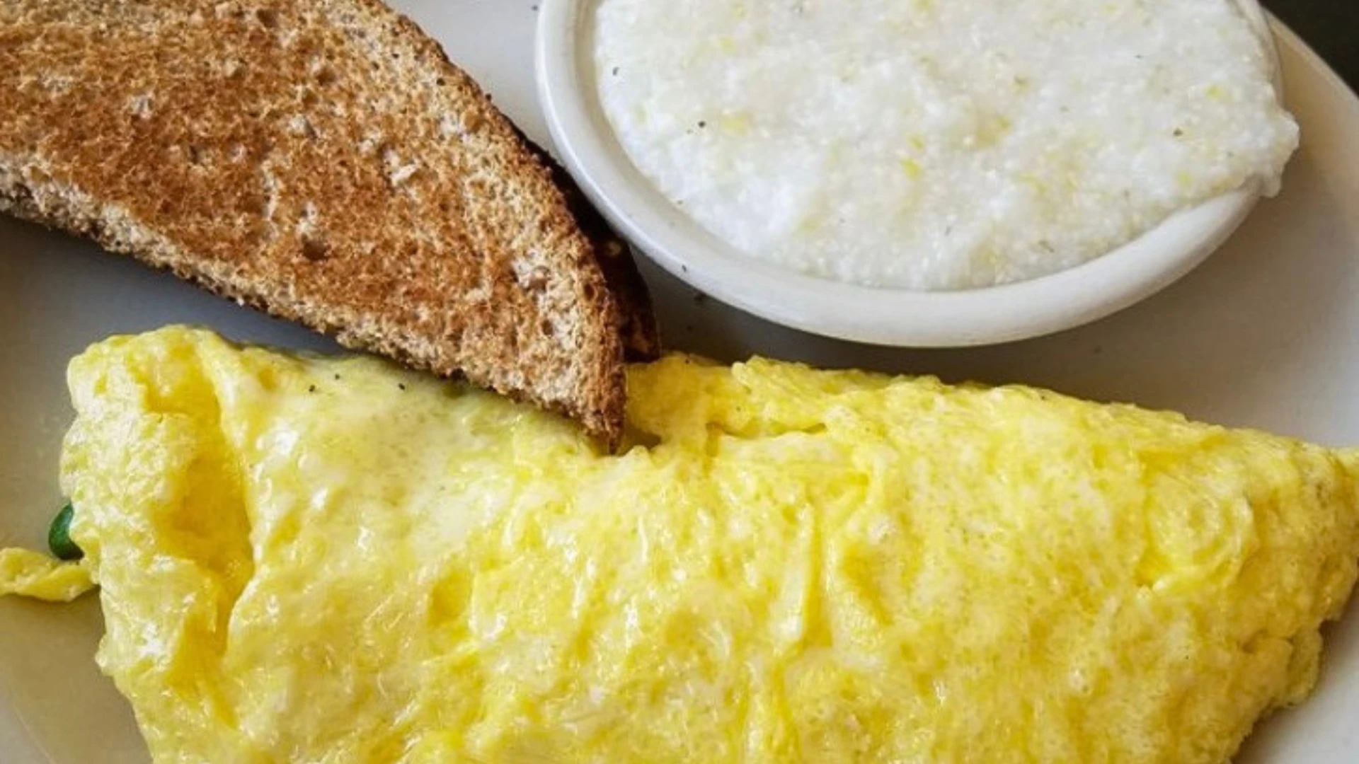 Cheese omelet breakfast plate with toast and creamy grits