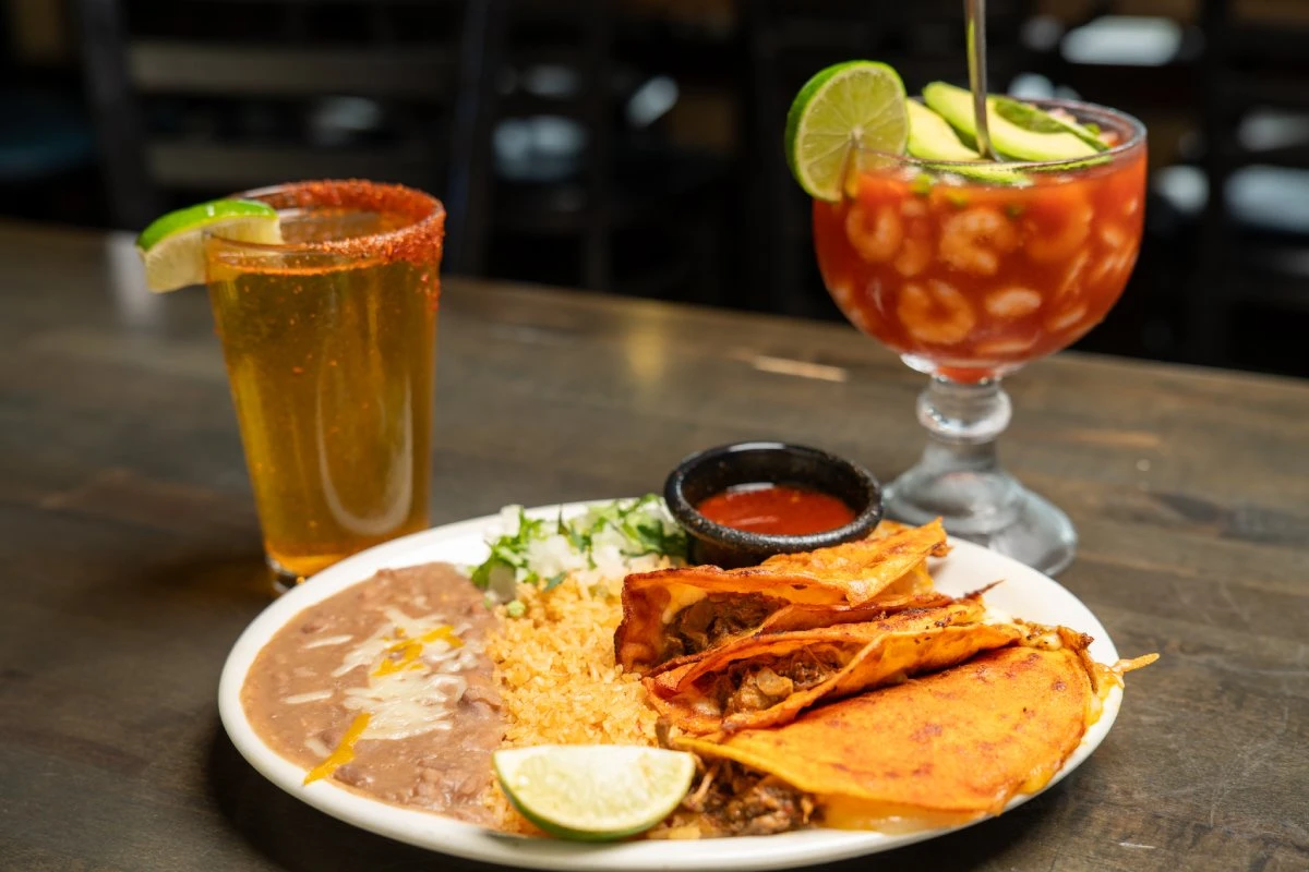 Quesabirria tacos with Mexican rice, refried beans, and salsa, served with a michelada and a shrimp cocktail at Primo's Tex Mex Grille