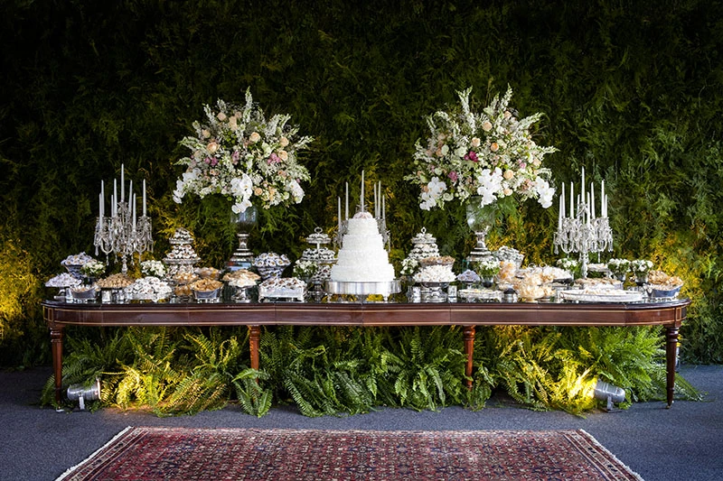A display table set against a wall of white florals and greenery