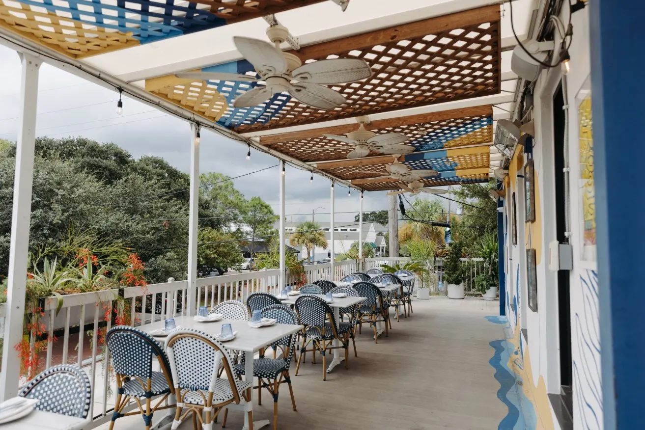 The covered second floor balcony at Junior’s on Harrison, set with tables and chairs overlooking the street
