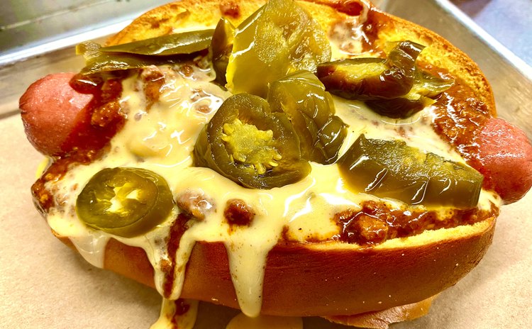 Nathan's hot dog topped with chili, queso and pickled jalapeños