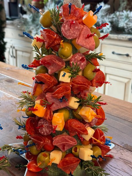 A Christmas tree built from skewered salami, cheese cubes, olives and rosemary