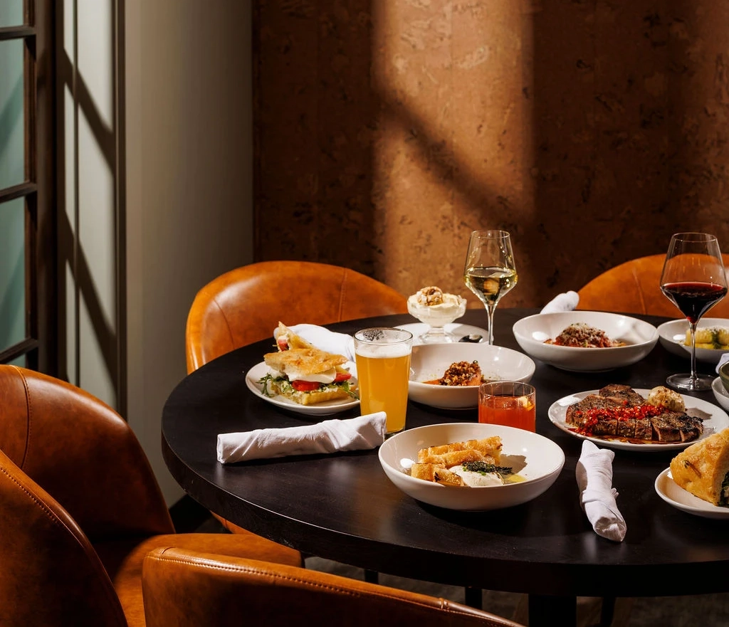Table set with assorted dishes, drinks, and wine in a warmly lit restaurant setting