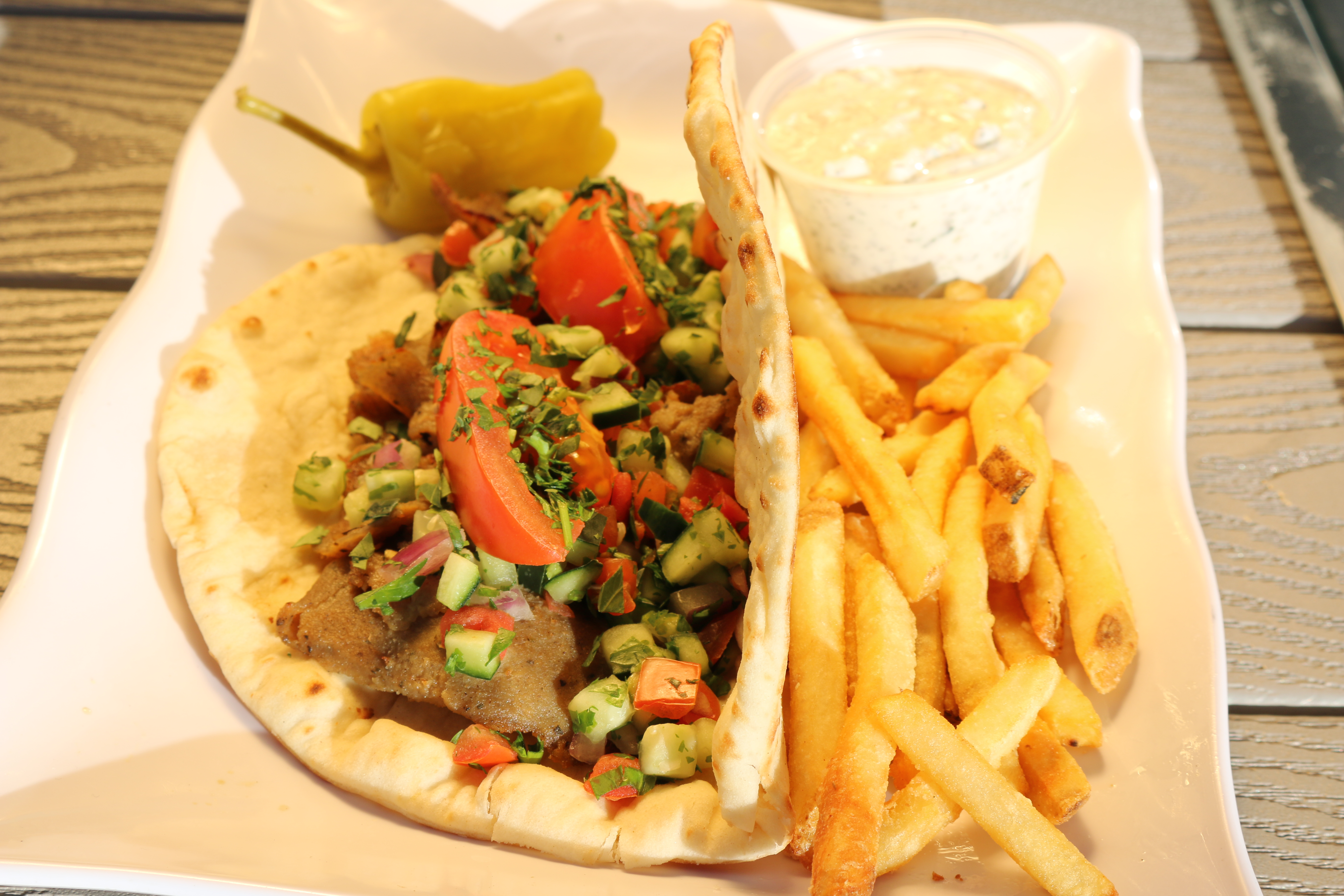 A traditional gyro topped with tomato wedges, parsley, & shirazi. Served with a side of fries.