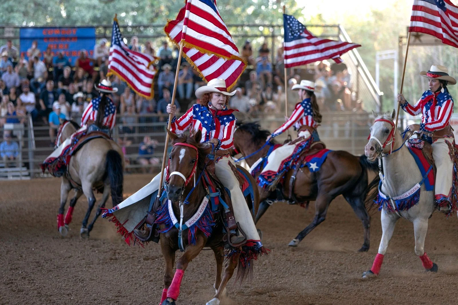 cowgirls and cowboys holding American flags.