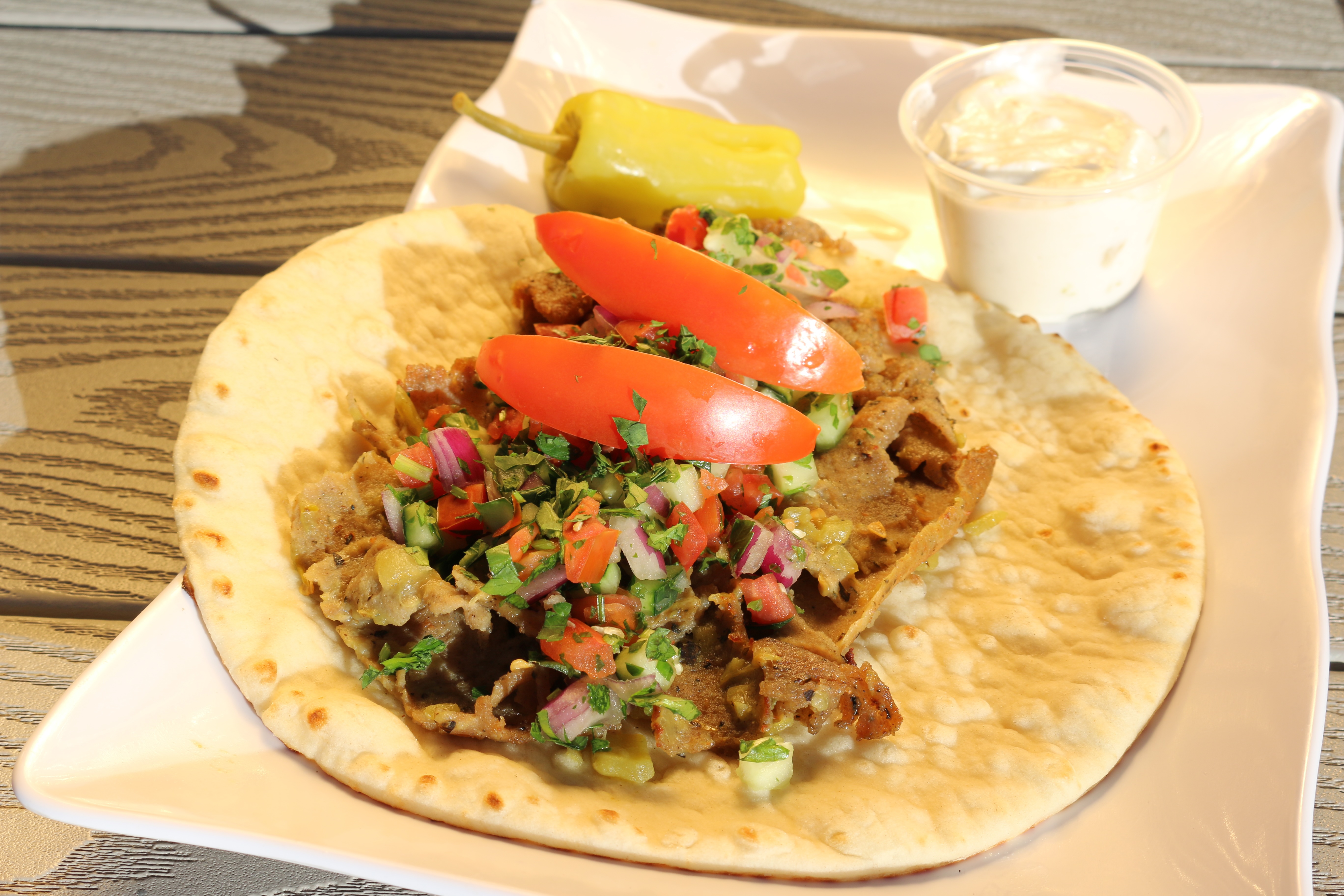 A New Mexico Gyro topped with green chile, tomato wedges, parsley, & shirazi.