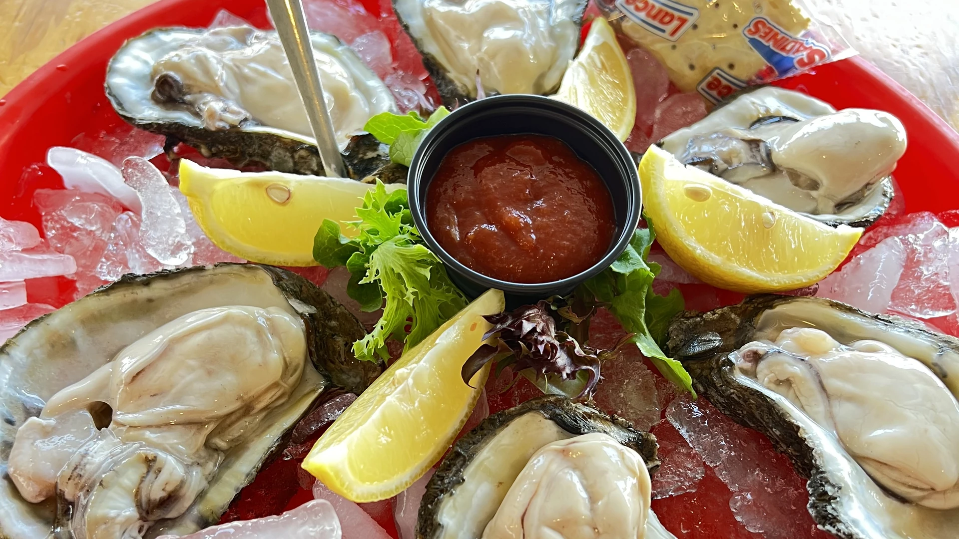 Fresh raw oysters on the half shell served over ice with lemon wedges and cocktail sauce.