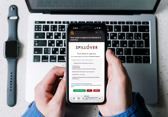 Spillover approval notification on a phone held over a laptop, showing a post ready to approve