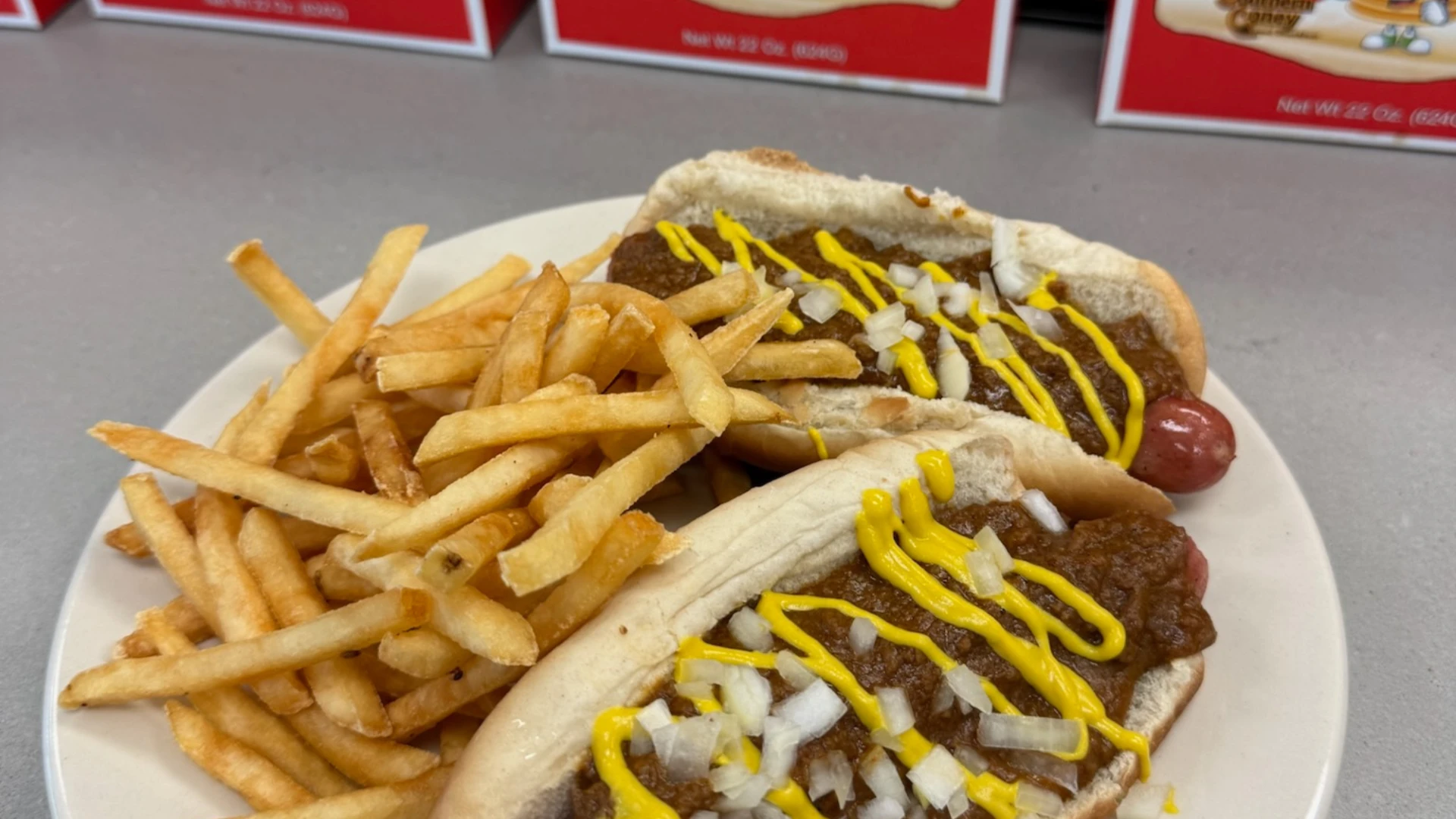 Chili cheese hot dogs with mustard and onions served with french fries