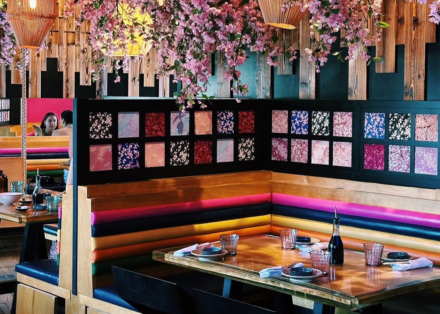 Colorful restaurant booth seating with cherry blossom decor, wood accents, and vibrant wall art