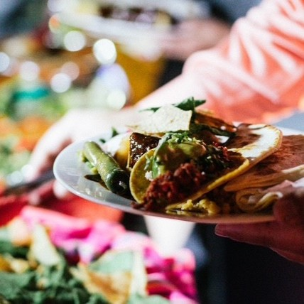 Someone getting food from the catering table