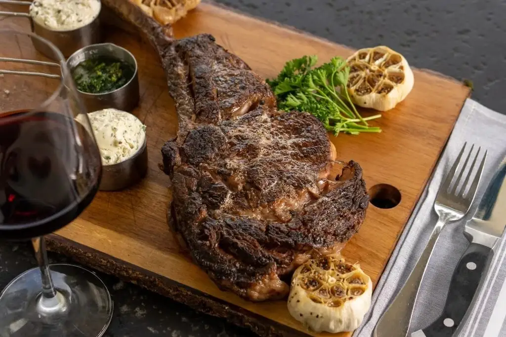 Grilled ribeye with roasted garlic on a carving board