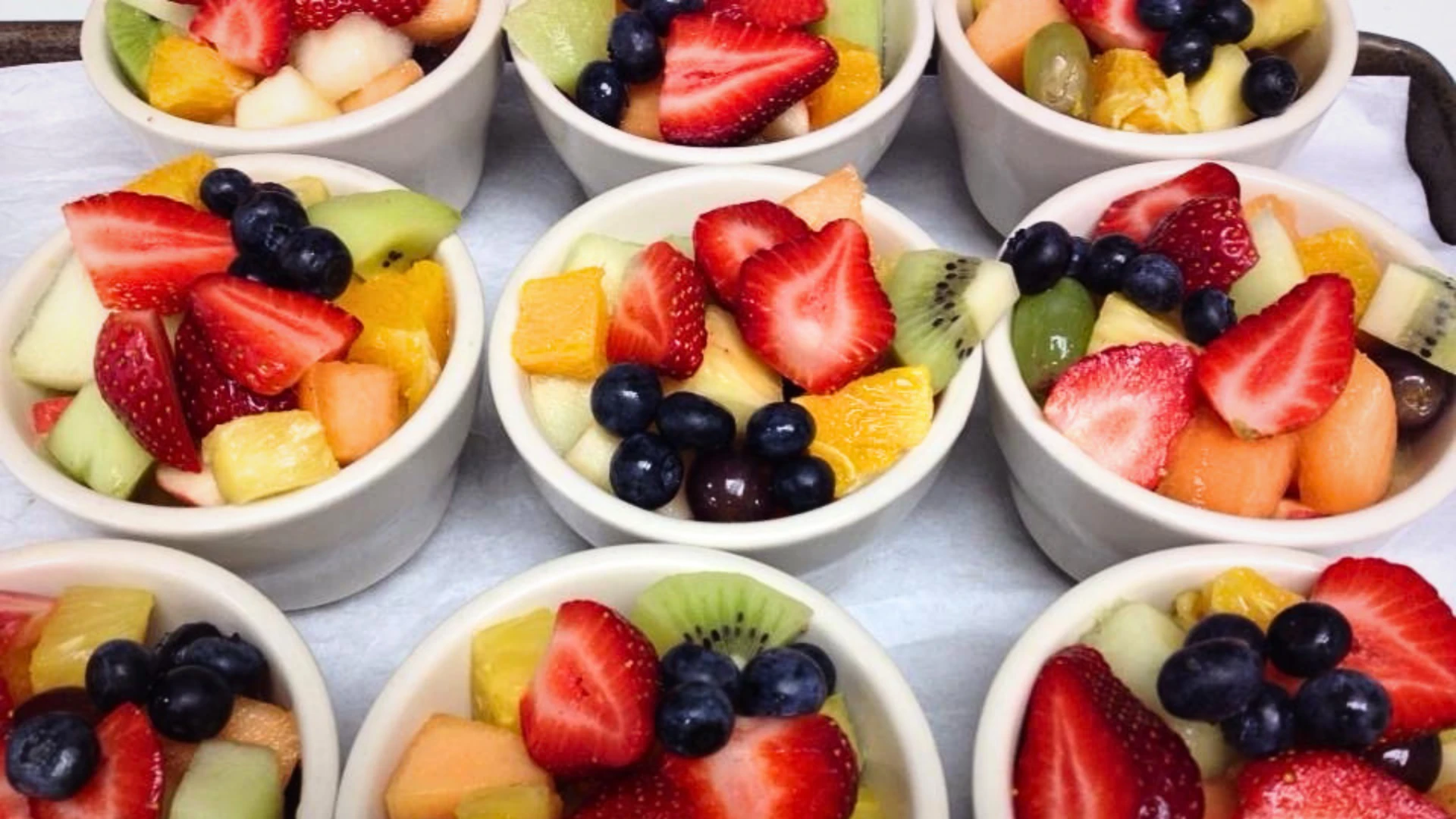 Fresh assorted fruit cups with strawberries, blueberries, kiwi, melon, and grapes