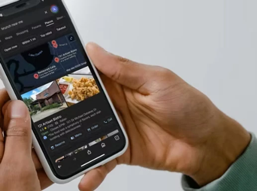 Guest holding a phone showing local search results for lunch nearby, with restaurant listings, photos, and ratings