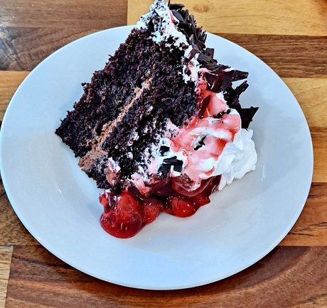 A slice of Black Forest cake with cherries and whipped cream